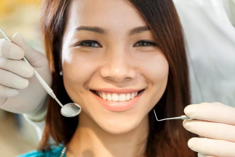uśmiechnięta kobieta i narzędzia dentystyczne